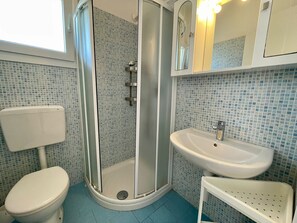 Un baño con ducha, inodoro, lavamanos y espejo.