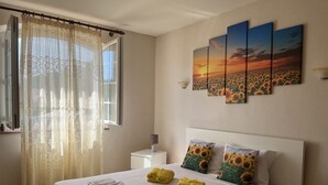 A neatly made bed with towels, a bedside table with a lamp, and a window with sheer curtains. - Charming 220m² Villa, 5 bedrooms, pool (heated), in Provence, 4-star **** rated (Bollène)