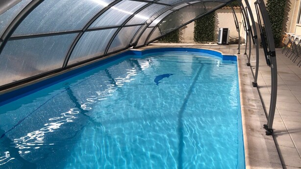An indoor swimming pool with a glass ceiling, surrounded by a tiled deck and a metal pool ladder. - Charming 220m² Villa, 5 bedrooms, pool (heated), in Provence, 4-star **** rated (Bollène)