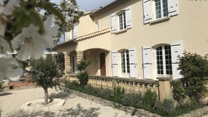 A two-story building with white shutters, a stone facade, and a garden with trees and shrubs. - Charming 220m² Villa, 5 bedrooms, pool (heated), in Provence, 4-star **** rated (Bollène)