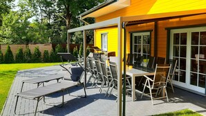 An outdoor patio with a table and chairs, a grill, and a covered seating area.