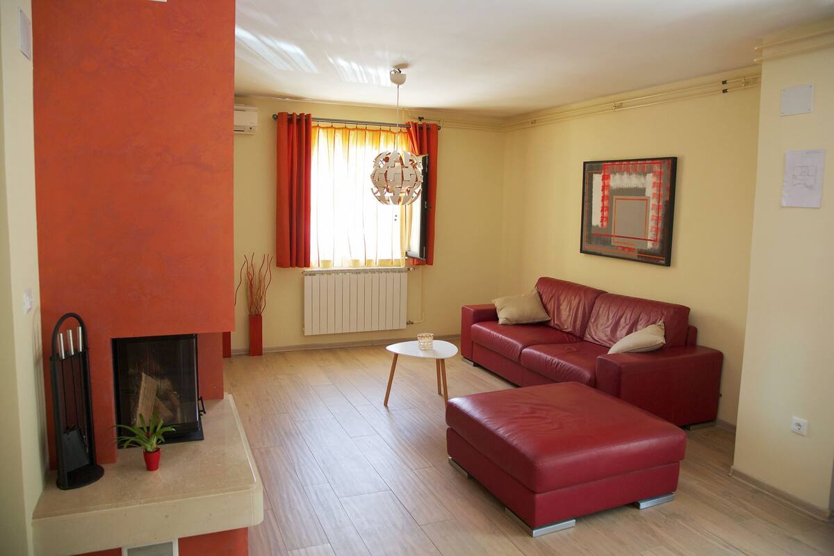 A living room with a red sofa, a small white table, and a fireplace.