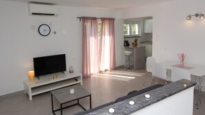 A modern living room with a flat-screen TV, a small table, and a seating area. - Apartments Polenta (Rovinj)
