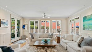Ein geräumiges Wohnzimmer mit einer großen Couch, einem Couchtisch und einem Deckenventilator.