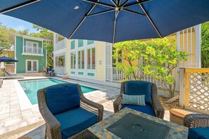 Un espace aménagé au bord de la piscine, avec des meubles en osier et un grand parasol.