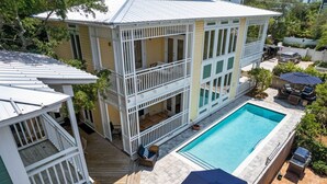 Ein zweistöckiges Haus mit Swimmingpool, Terrasse und Gartenmöbeln.