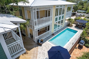 A two-story house with a swimming pool, deck, and outdoor furniture.