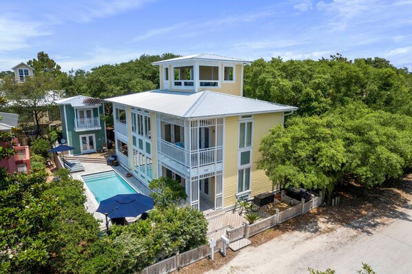 Une maison à deux étages dotée d’une grande terrasse et d’une piscine.