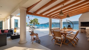 A covered outdoor area with a dining table, chairs, and a grill.