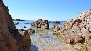 Eine felsige Küstenlandschaft mit klarem, flachem Wasser und großen Felsen.