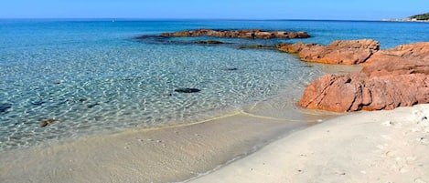 Une plage propre, avec des formations rocheuses et une eau calme.