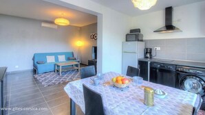 A modern kitchen with a dishwasher, a washing machine, and a dining area with a table set for two. - Apartment **** sea view in the heart of the Corsican maquis, 5 mm from the beach (Cargèse)