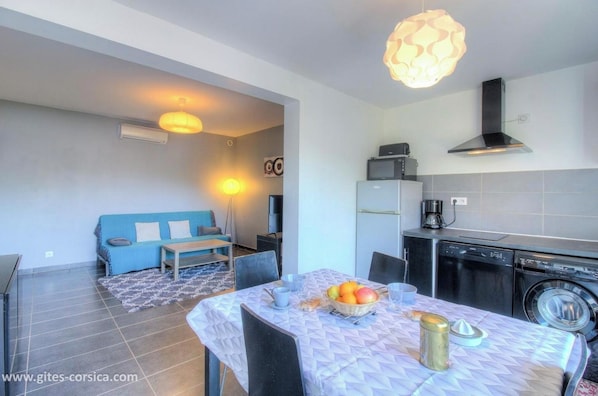 Une cuisine moderne équipée d’un lave-vaisselle, d’un lave-linge et d’un coin repas avec une table dressée pour deux personnes.