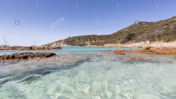 A coastal landscape with clear turquoise waters, rocky formations, and a hilly backdrop. - Apartment **** sea view in the heart of the Corsican maquis, 5 mm from the beach (Cargèse)