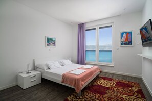 Een slaapkamer met een bed, een nachtkastje, een raam met uitzicht en kunstwerken aan de muur.