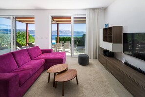 Un salon moderne avec un canapé rose, une table basse en bois et un téléviseur posé sur un meuble en bois.