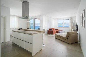 Een moderne keuken met een centraal eiland, een zithoek met een bank en een tafel, en een woonruimte met een bank en salontafel.