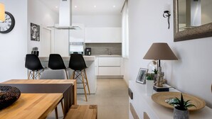A modern kitchen with white cabinets, a built-in stove, and a dining area with a wooden table and chairs.