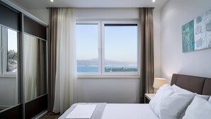 A hotel room with a bed, a window with a view, a nightstand, and a lamp.