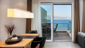 A modern hotel room with a balcony, a dining area, and a view of the sea.