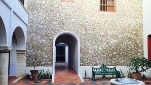 Un patio interior con pared de piedra, un banco y una jardinera.