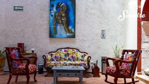 Una habitación con un sofá, dos mecedoras, una mesa de centro y un cuadro en la pared.
