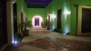 Un pasillo con paredes verdes y suelo de baldosas, que conduce a una puerta con marco azul.