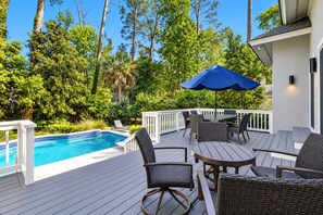 Une terrasse avec une piscine, du mobilier d  ’extérieur et un parasol bleu.