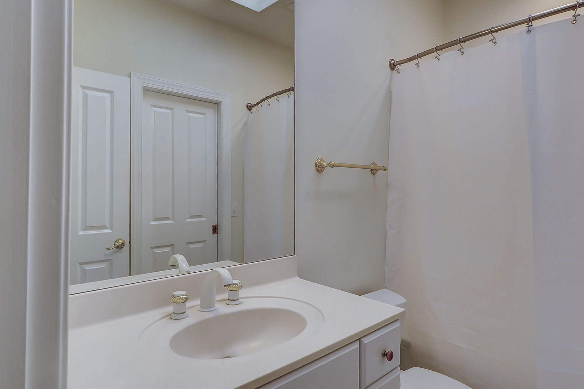 A bathroom with a white sink, a mirror, and a shower curtain.