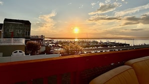 Een zonsondergang uitzicht vanaf een balkon met uitzicht op een jachthaven met aangemeerde boten.