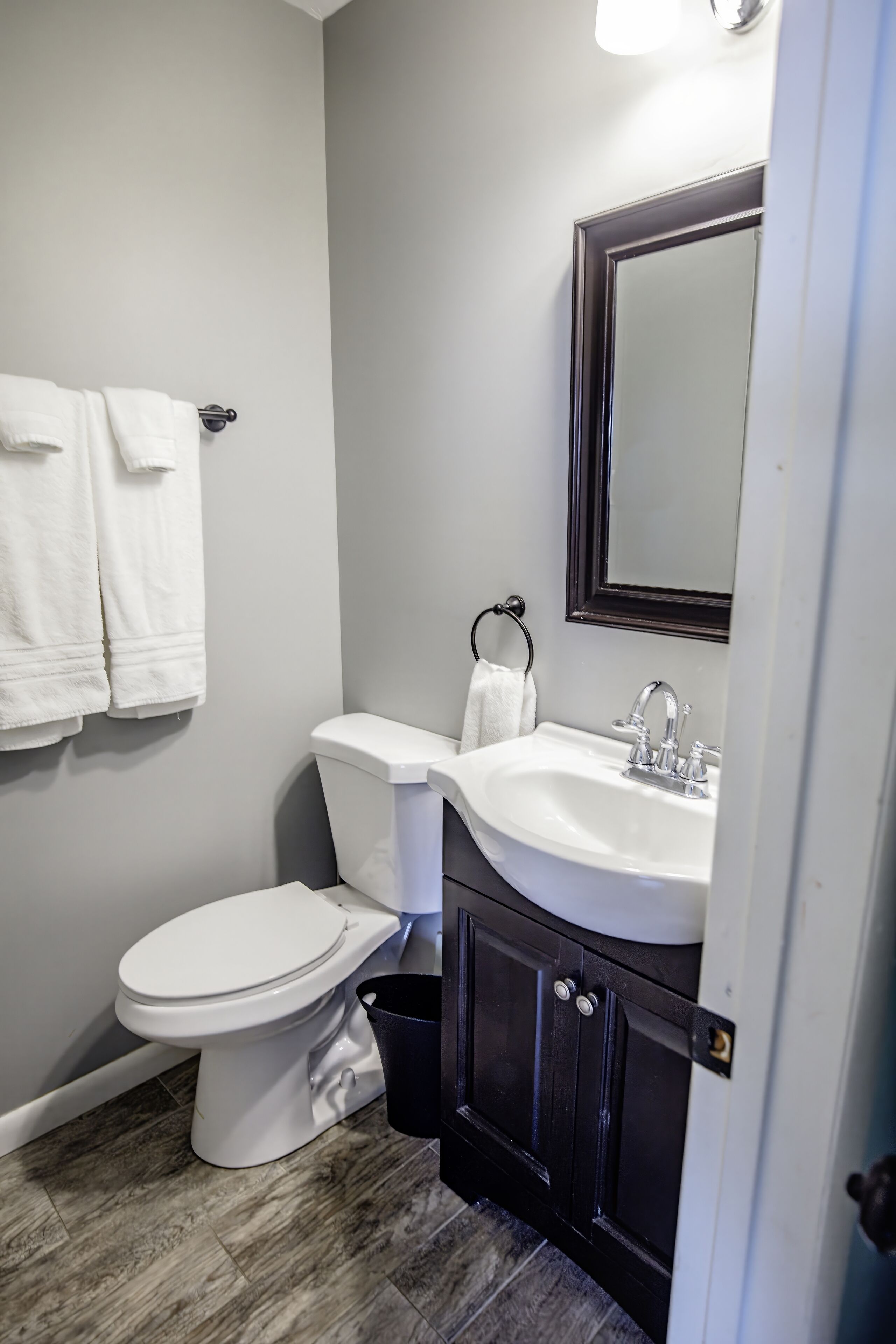 A bathroom with a white toilet, a sink with a mirror above it, and two towels hanging on hooks.