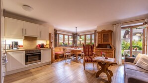 Une cuisine spacieuse avec des meubles de rangement en bois, un coin repas avec une table et des chaises en bois, et un coin salon confortable avec un canapé.