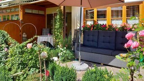 Un jardin avec un espace patio, un canapé et une table placés sous un grand parasol.