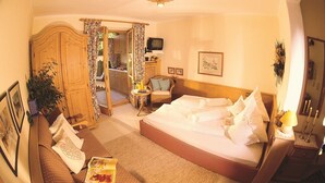 Een hotelkamer met een bed, een kleintje tafeltje, een televisie en een kledingkast.