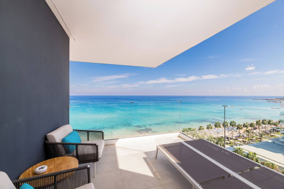 A balcony with a view of the ocean, a pool table, and outdoor seating.