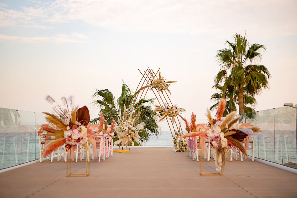 An outdoor wedding setup with floral arrangements and palm trees.