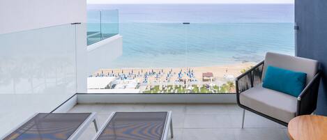 Un balcón con vista a la playa, un sofá y dos sillones.
