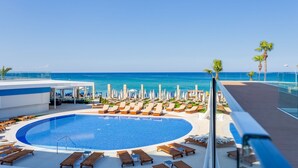 A pool area with lounge chairs and umbrellas, overlooking a beach and ocean. - Flamingo Paradise Beach Hotel Adults Only (Paralimni)