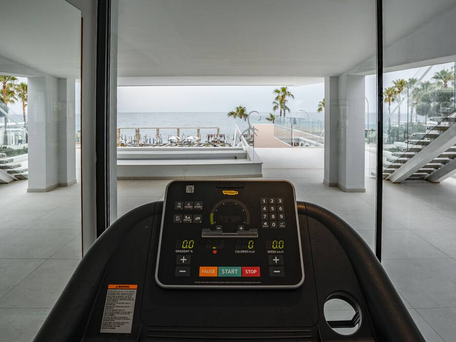 Un tapis roulant con display digitale, vista su una spiaggia e un design architettonico moderno.