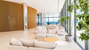 A spacious lobby with modern furniture, large windows, and a view of the ocean. - Flamingo Paradise Beach Hotel Adults Only (Paralimni)