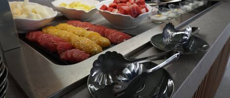A buffet with various fruits and vegetables, including apples, oranges, and watermelon.