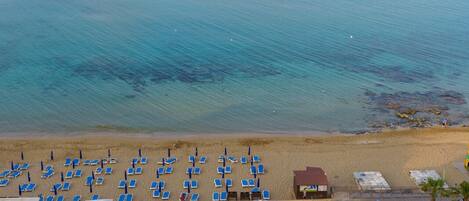 Un resort con piscina, sillas de playa y sombrillas.