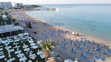 En la playa, arena blanca, sillas reclinables de playa, sombrillas