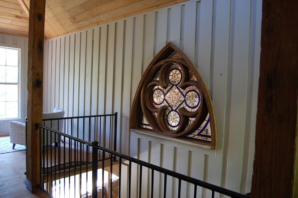A staircase with a wooden railing leading to a room with a decorative stained glass window.