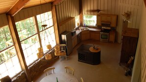 Una cocina rústica con armarios de madera, una estufa y un comedor con mesa y sillas.