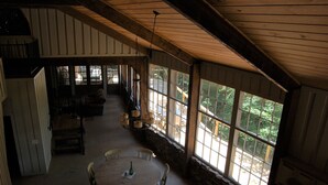 Una habitación amplia con techo alto, ventanas grandes y un comedor con mesa y sillas redondas.