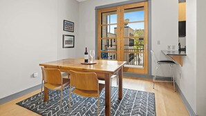 Een eetgedeelte met een houten tafel en stoelen, een tapijt met patroon, een fles wijn en glazen op de tafel.