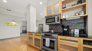 Een moderne keuken met houten kastjes, een oven van roestvrij staal, een magnetron en een achterwand van baksteen.