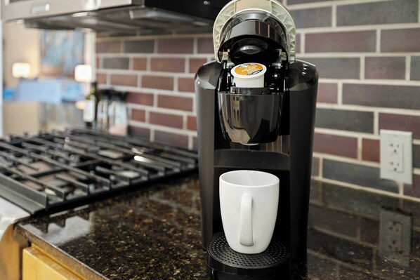 A coffee maker on a kitchen counter with a brick backsplash.