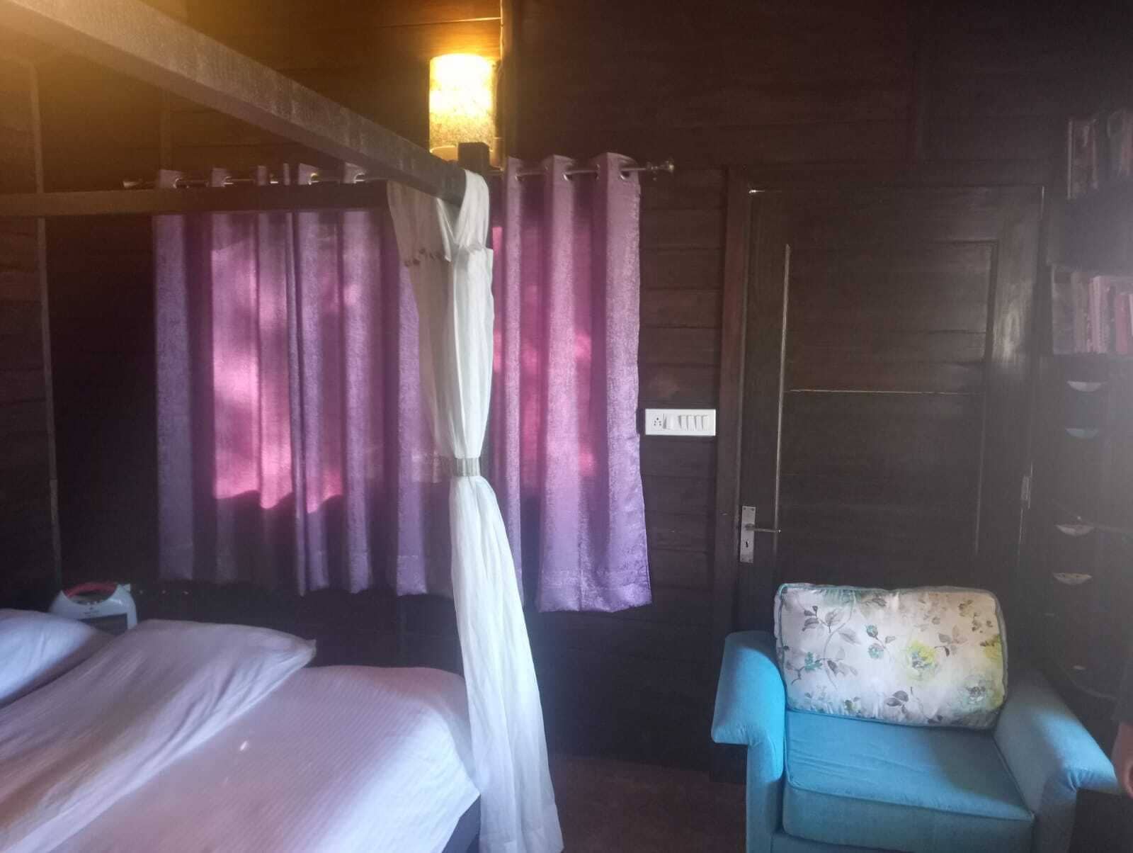 A room with a bed, a chair, and a curtain.